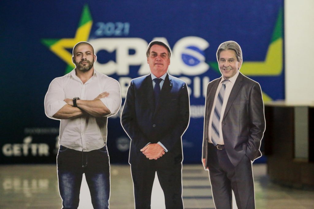 sayap kanan CPAC 2021: Figur karton Presiden Bolsonaro (tengah), Anggota Kongres Daniel Silveira (kiri), dan mantan Anggota Kongres Roberto Jefferson.  Keduanya mengapit Tuan.  Bolsonaro ditangkap karena mengancam hakim Mahkamah Agung.